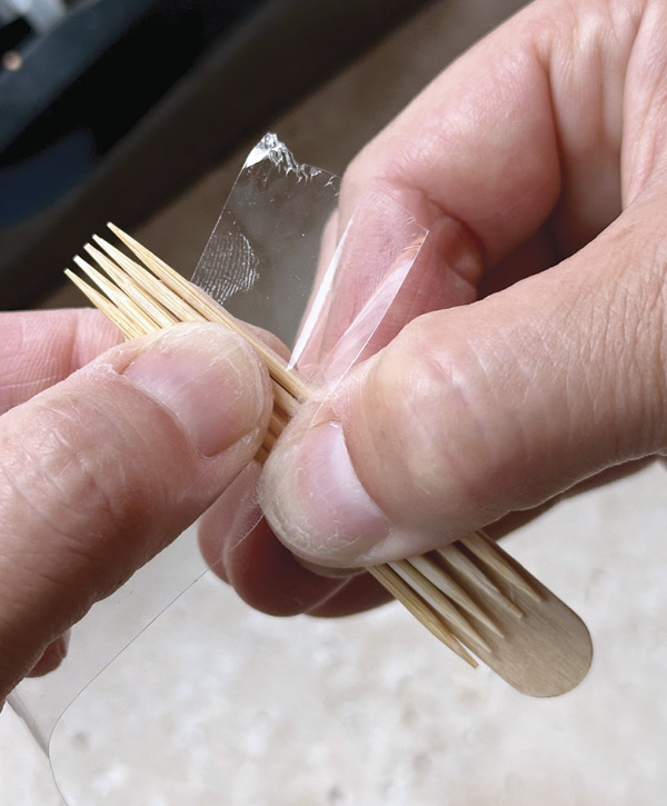 3 Hold the stick securely while neatly wrapping the tape around the toothpicks and wooden craft stick so they hold together firmly.