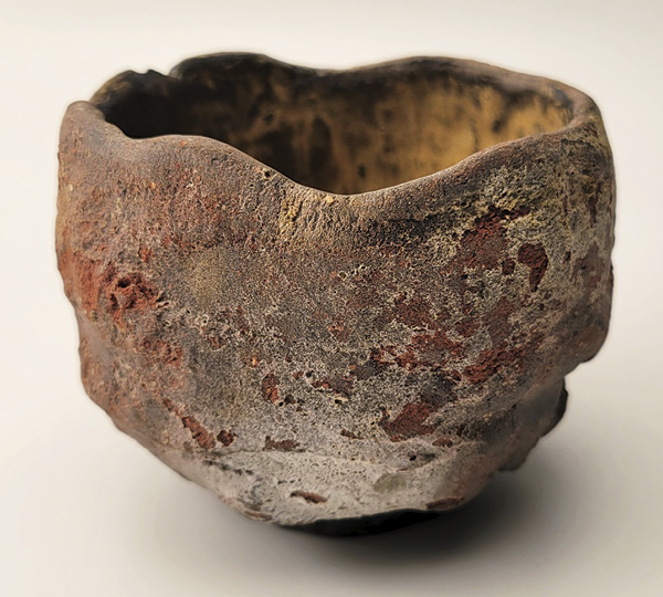 5 Weathering and Erosion, 5 in. (12.7 cm) in diameter, mid-fired black clay, wheel thrown, altered, crushed sandstone pressed onto the sidewalls of the piece at the wet stage, lightly sprayed with multiple glazes and ash, fired in oxidation to cone 6, 2022.