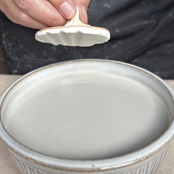 2 Hold the putty while dipping the face of the ornament in glaze.