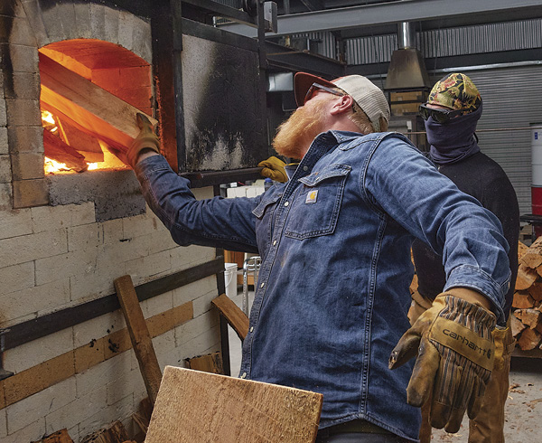 11 Haas finding space to put more wood in the train-kiln firebox at Red Lodge Clay Center’s 20th Anniversary firing. David Hiltner holds the firebox door open for Haas.