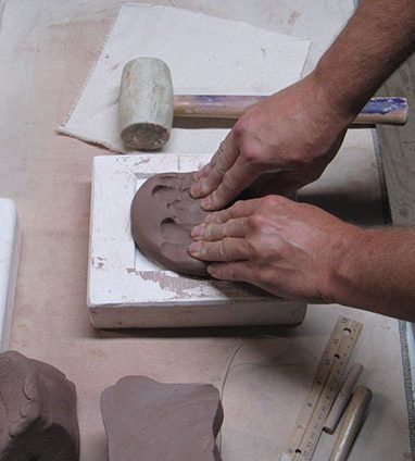 13 Press a large piece of soft clay into the mold by hand. 