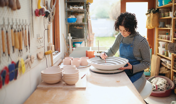 2 Sharon Alpren adding terra sigillata to a large bedrock bowl in her home studio, accompanied by her dalmatian, Lottie. Photo: Andrew Craig.