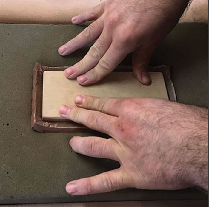 7 Sandwich the plastic-covered clay between foam and the wooden block template. Press down to create the plate.