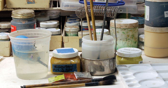 Linda Arbuckle’s studio brush holder is a converted watercolor brush washer that uses a recycled plastic jar instead of the perforated tray that is typically included with the holder.