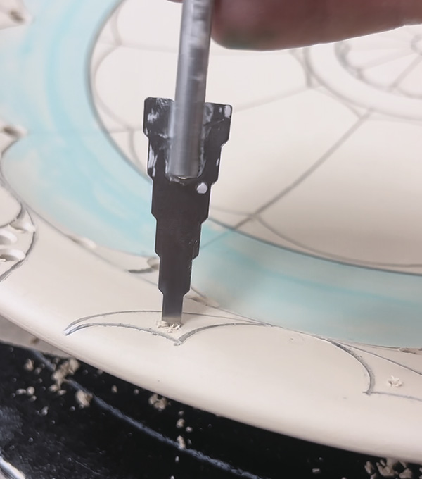2 After drawing and carving lines on the platter, use drill bits to perforate various-sized holes through the clay.
