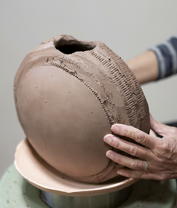 16 Gently compress the sides by rotating and tapping the vase into the bisque form, rotating as you work.