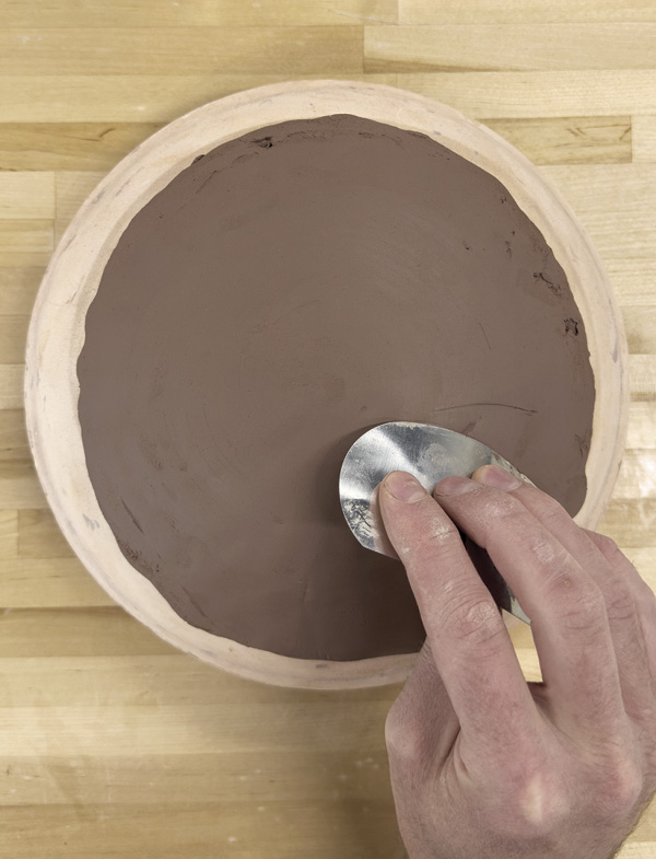 2 Flip the stamped slap over onto a mold. Compress it to fit the shallow bowl form.