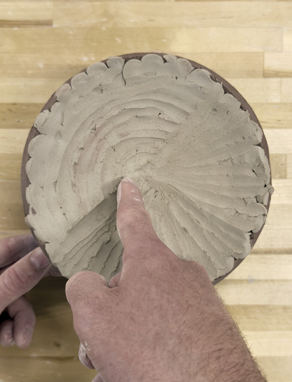 5 Compress the clay into the stamped and slipped surface with a finger.