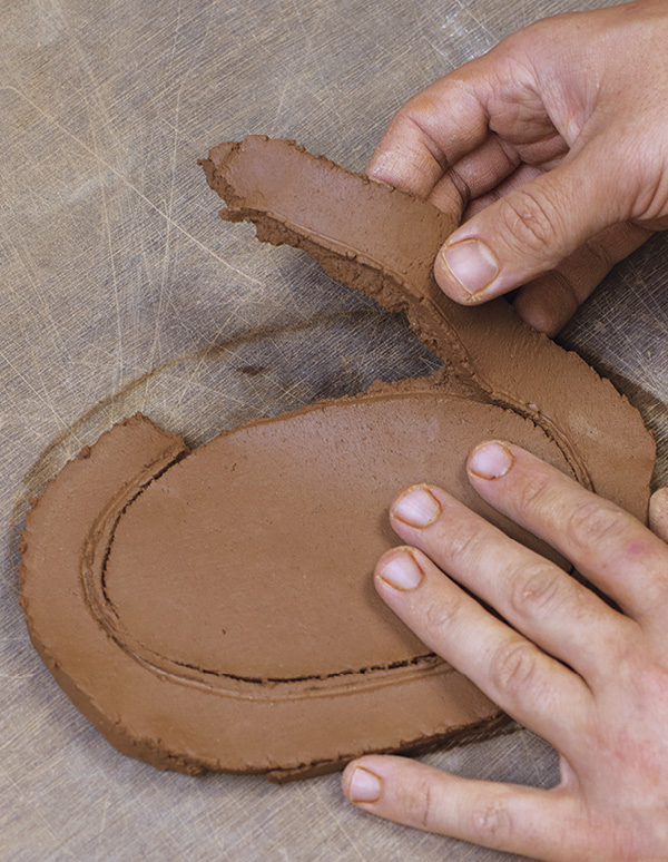 6 Holding down with one hand, use your other hand to pull the excess clay away.