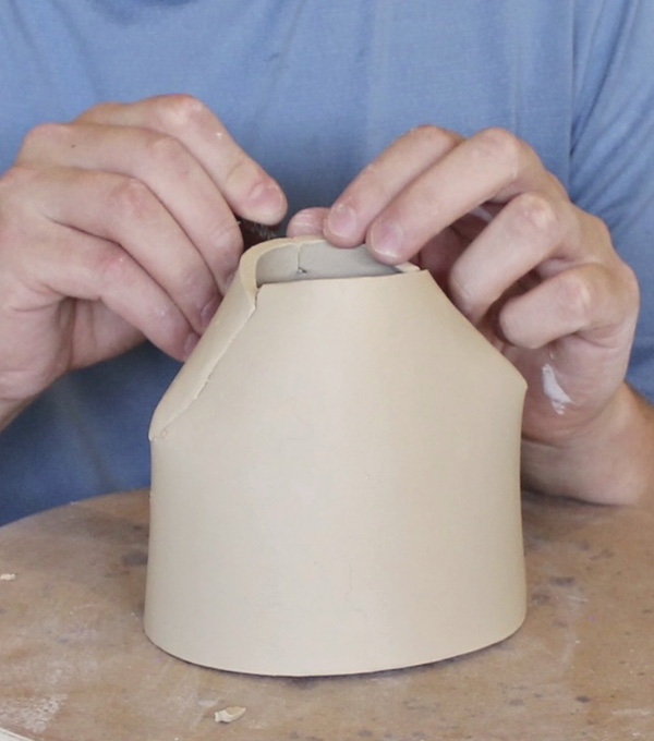 1 Start with a thin, handbuilt cylinder, cut four evenly spaced darts, and collar the base inward. Keep the clay soft.