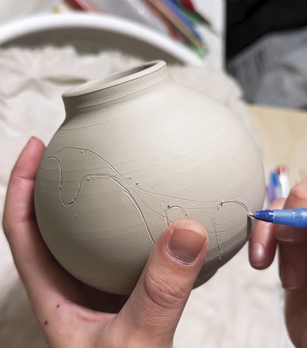 1 Draw a line around the pot, which is on the softer side, to mark the top and the bottom, then sketch a drip design.