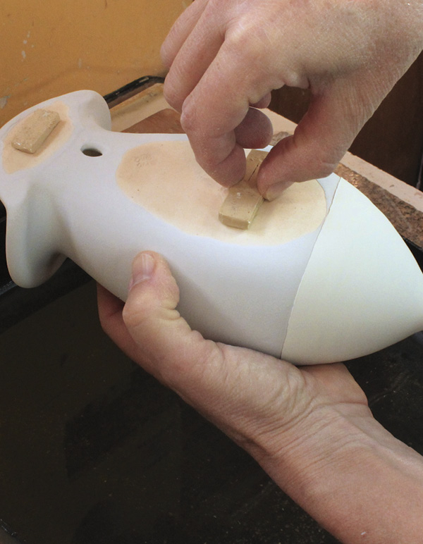 15 After glazing, attach stilts made of bisque clay to the waxed areas.