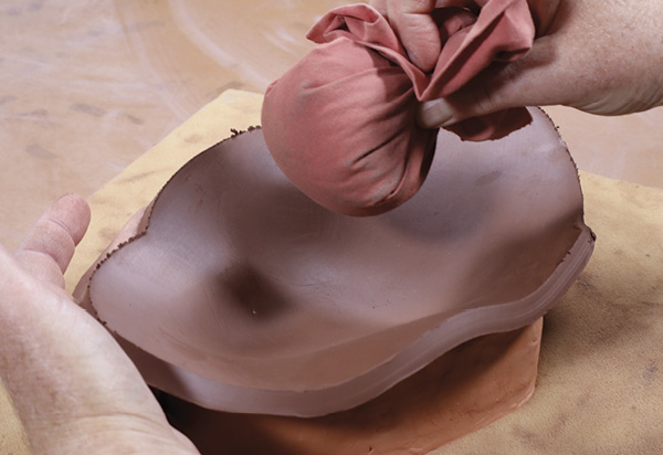 3 Drape the slab over the mold. Use a pouncing pad or damp sponge to create volume. Lift the outside edge as you tap.