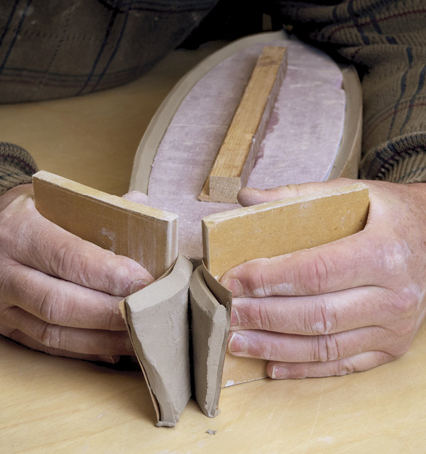6 Use two pieces of wood to squeeze the ends of the wall sections together.
