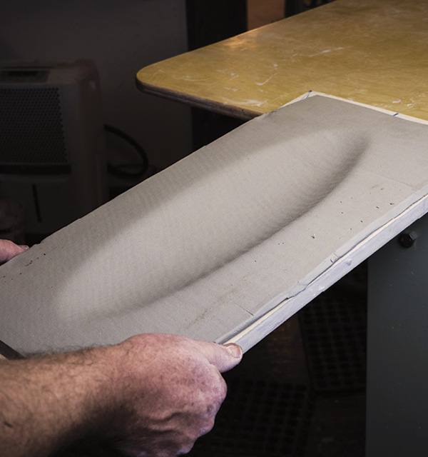 7 Tap the edges of the slump mold on the edge of a sturdy table to slump the clay.