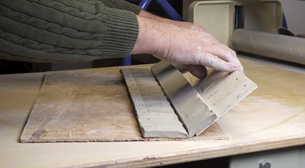 7 Apply Magic Water to the hinge, then slide the template under the clay hinge and raise up the foot of the tile.