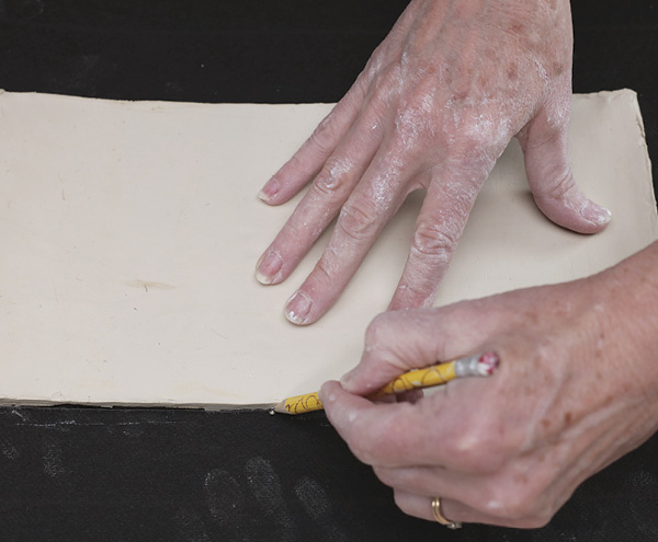 4 Remove the slab from the tube without stretching it, lay it flat on the tar paper, and trace around the rectangular clay slab.