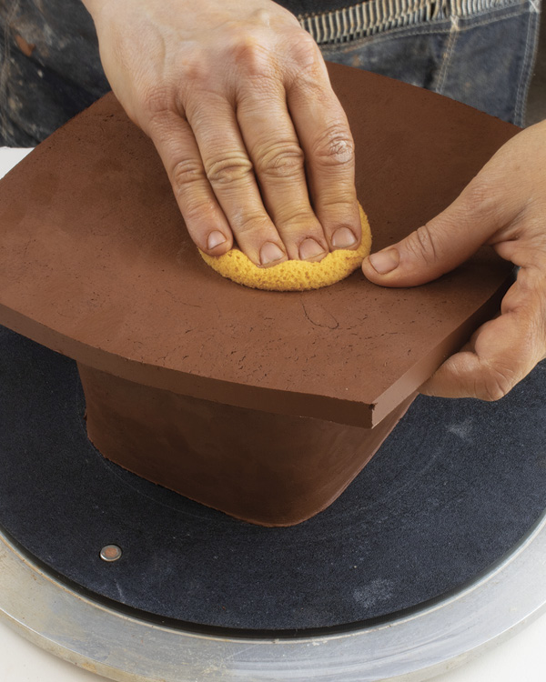 8 Using a sponge or soft rib, coax the slab down into the lid to create a slight curve.