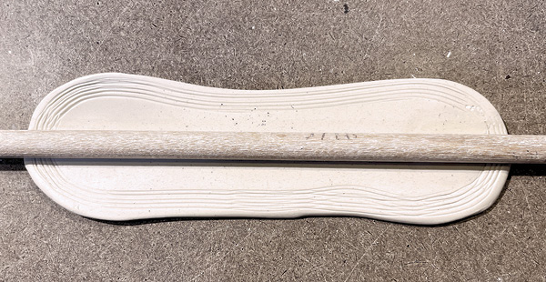 C2 Cut out the form from the slab. Lay a dowel in the center along the length of the clay piece.