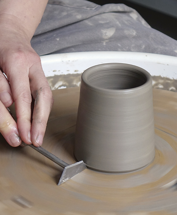 4 Using a knife-like tool, take away the skirt of clay at the base or the cylinder, so the form has lift from the tabletop.