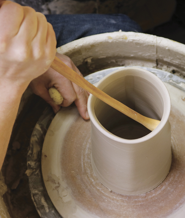 2 Working from the base to the lip on all four sides of the pot, square the cylinder with a shaping stick.