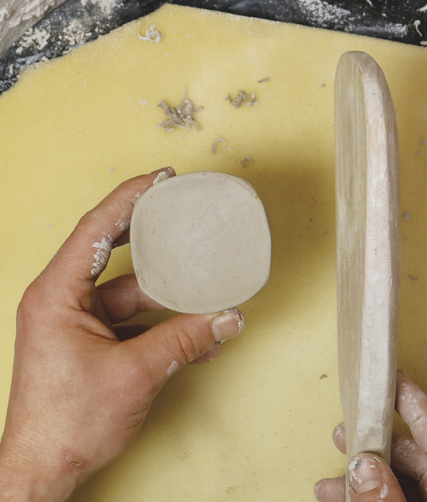 10 Paddle the leather-hard bell into a square shape similar to the form and edge work already on the pot and the handle.