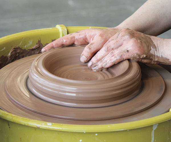 1 Working on a bat, center a ball of clay into a low puck shape, and then open.