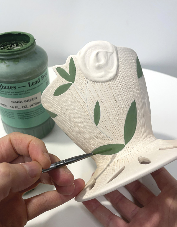 14 After bisque firing, paint leaves onto the surface of both pieces using underglaze.
