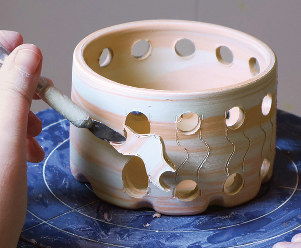7 Draw your design in between each of the holes. Cut along the drawn lines and remove the clay to reveal a design.