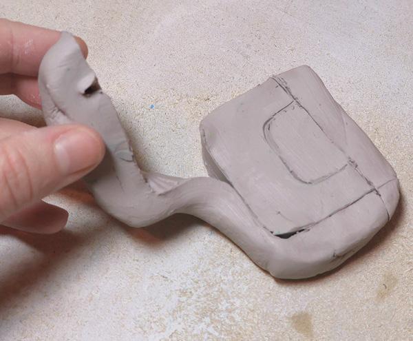 8 Draw then cut a handle from a thick block of colored clay. Remove the excess clay.