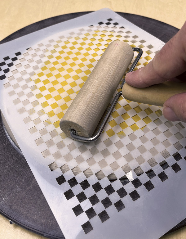 3 Place a stencil on the disk and roll a pony roller over it to seal it to the clay.