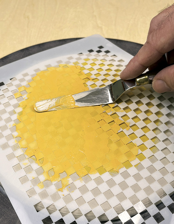 4 Spread a second color of underglaze across the stencil surface.