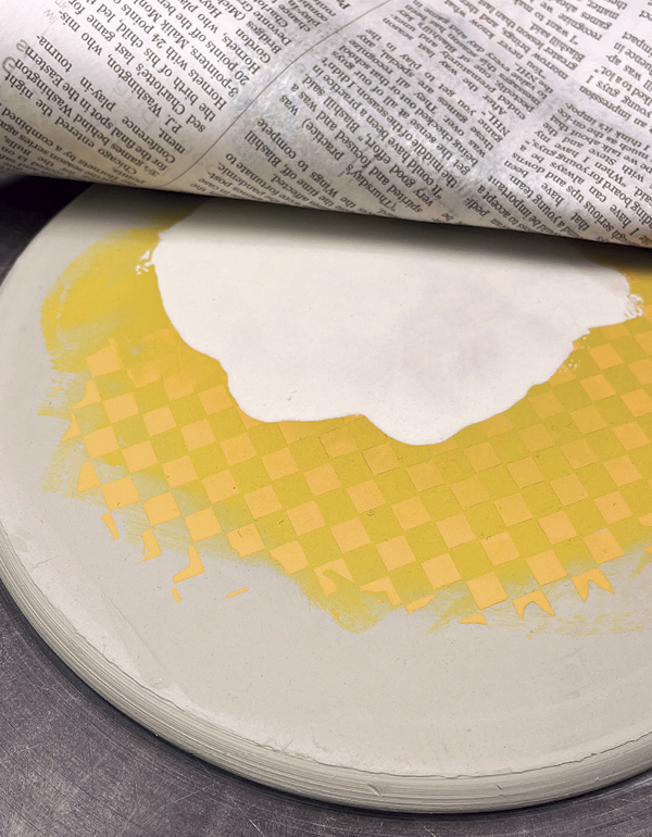 8 Place dry newsprint over the dry raised design and roll the surface flat.