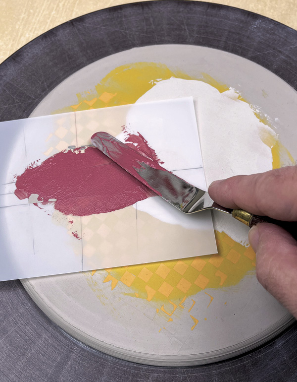 10 Spread red underglaze across the stencil’s opening with a palette knife.