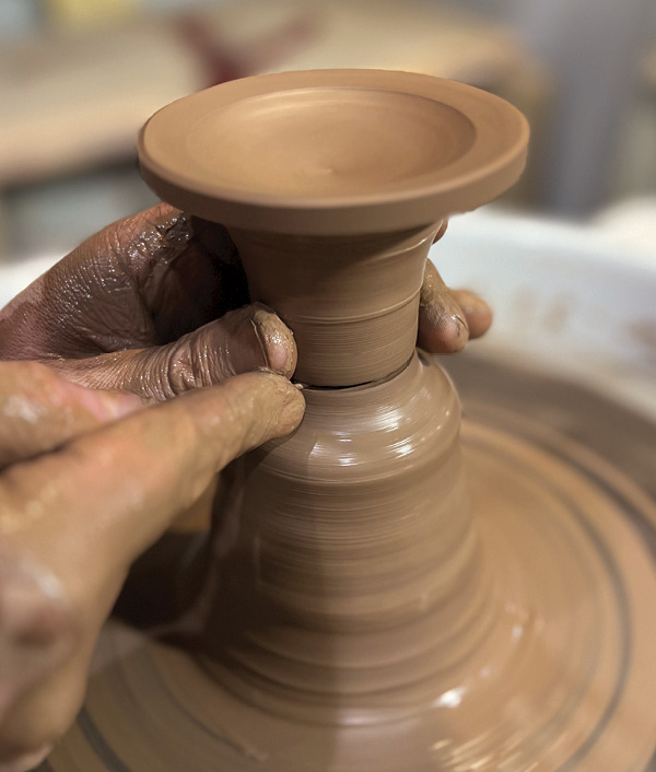 6 With the wheel slowly turning, use the tip of needle tool to cut the lid from the hump of clay on the wheel.