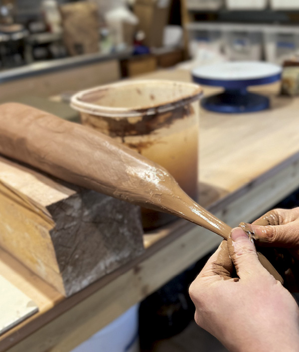 14 Secure a tapered log of clay to a table and use two hands to pull handles using both pushing and pulling motions.