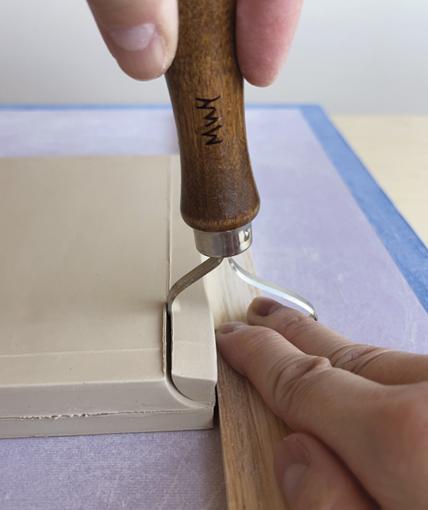 3 Hold your trimming tool on the shim and push the tool away from you to create an edge, then do a reverse pass.