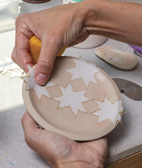4 Soak pre-cut paper stencils in water. Apply the wet paper stencils to the leather-hard pin dish.