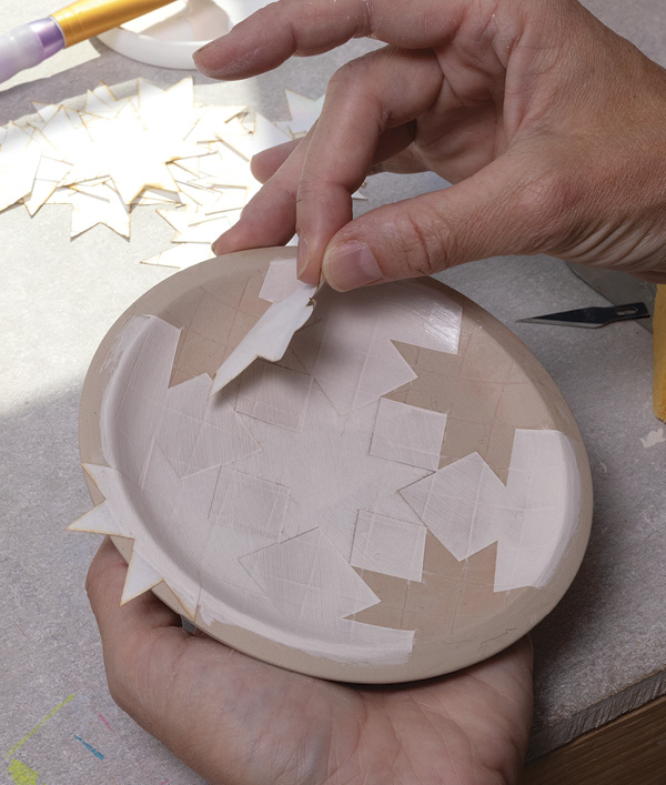 5 After painting underglaze over the stencils, carefully remove the stencils to reveal the design. Bisque fire dish.