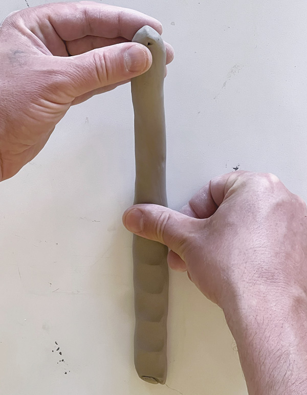 9 While holding one coil end up, press it against the table toward opposite end.