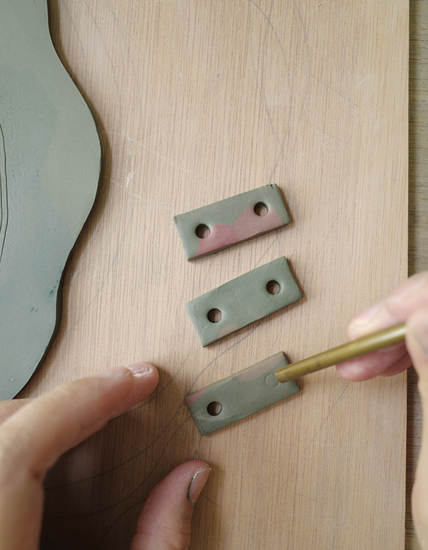 9 Use leftover clay to make three rectangular tabs and pierce two holes in each.
