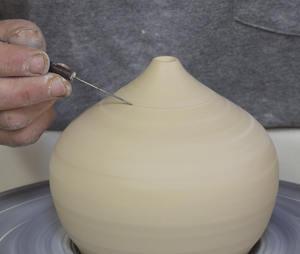 4 Allow to dry to a soft leather hard and trim any excess from the base. With the wheel turning, mark a line around the top with a needle tool.