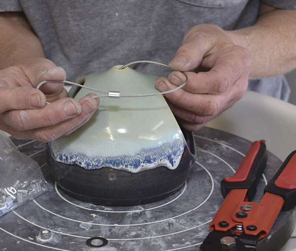 8 Use the crimping tool to cut 6–10 in. (15.2–25.4 cm) of cable. Thread a crimp onto the cable and then put the end through the crimp to create a loop.