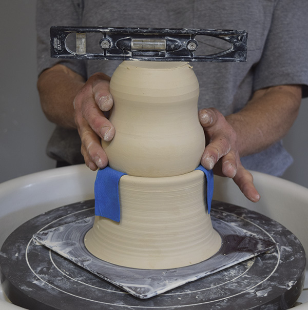 5 Level the bottle in the chuck—this is the only way to center it. The chuck is still centered on the bat, although if you use a bisque-fired chuck you’ll center the chuck first. Trim the bottom of the feeder bottle round and smooth.