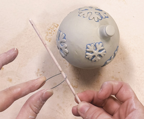 5 Use the hanging hardware rod to shape the high fire wire, then attach it to the top. Allow the ornament to slowly dry.