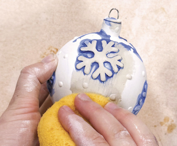 6 Wash the bone-dry surface with a dark blue underglaze and sponge off excess to create more contrast around snowflakes.