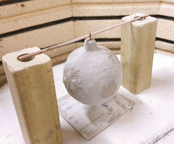 8 Hang the ornament in the kiln with the rod suspended over two kiln posts. Place a waste piece underneath the ornament.