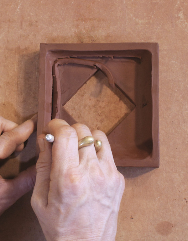 9 Press triangle tip into the smoothed coil and drag around interior perimeter.