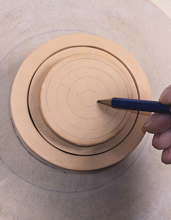 2 Center the piece on a wheel and use a pencil to create concentric circles.
