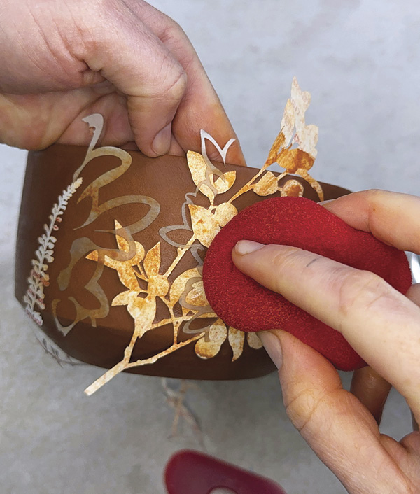 6 Squeegee the stencil down, then wipe away any excess colored slip.